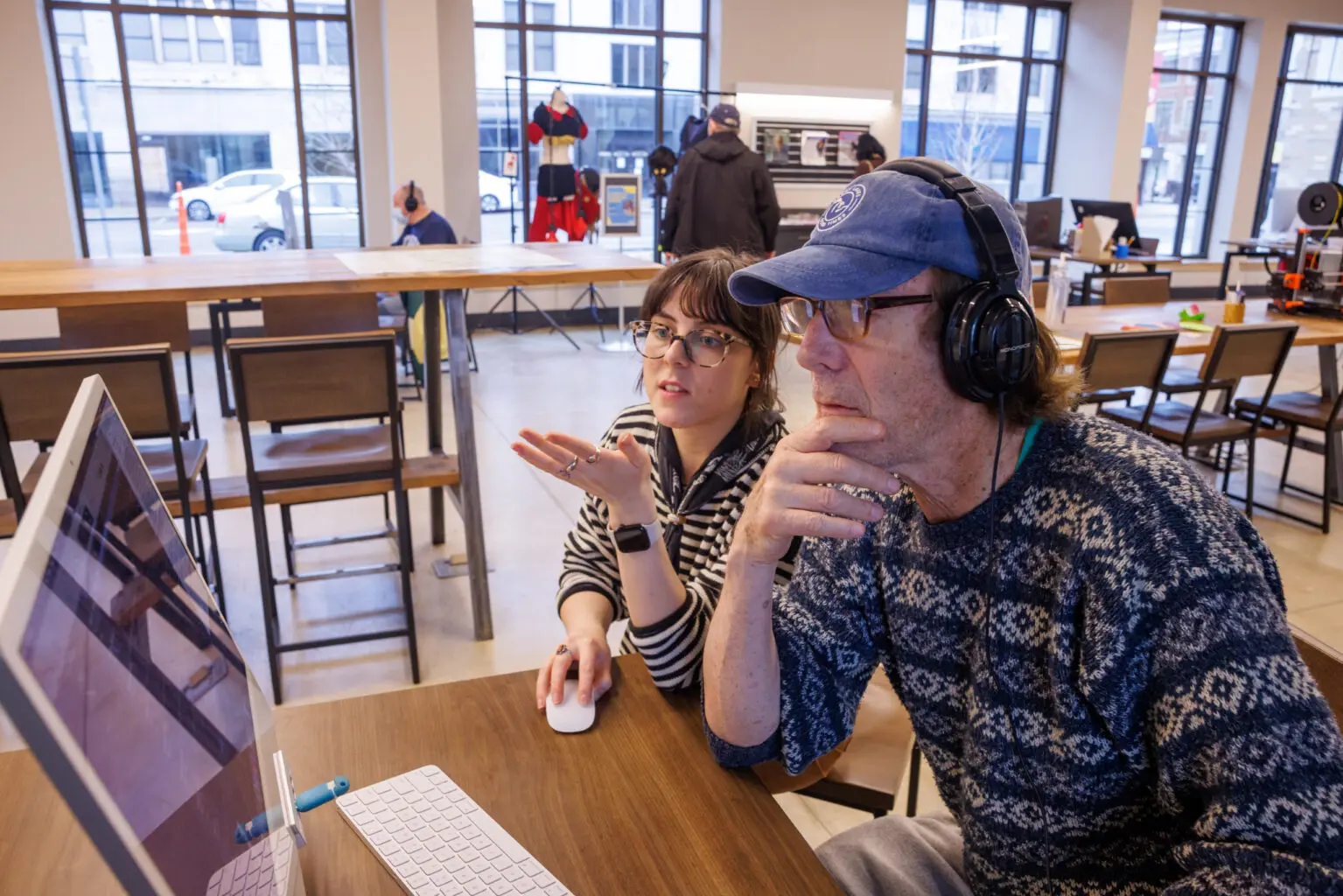 A librarian assisting a man at a computer.